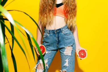 留着长头发在黄色背景上的女孩拿着新鲜的葡萄