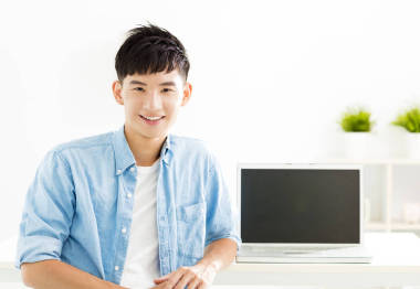 與筆記本電腦的亞洲年輕男人微笑