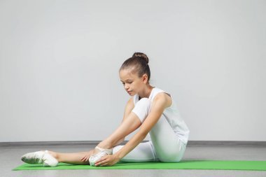 年輕姑娘做綠色瑜伽墊上練習(xí)