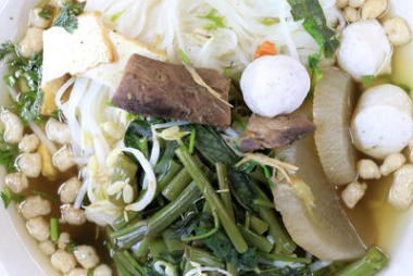 vietnamse 面條湯，配上新鮮草藥在佛教餐館、 蘿卜、 牽?；?、 香菇和素食節(jié)木桌上的白碗豆腐