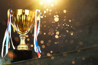 低调的金色奖杯在模糊的灰色背景与抽象闪亮的灯光 