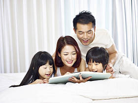 亚洲家庭有两个孩子躺在床上读书