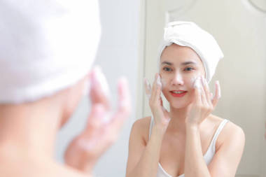 亞洲女人清洗臉上的皮膚享受自己與泡沫 cleansi