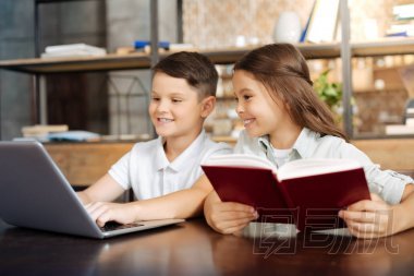 閱讀本書時她的弟弟在筆記本電腦上玩的小女孩
