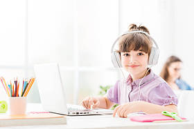 可爱的小女孩带着便携式计算机连接