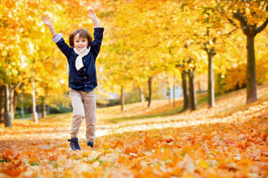快樂的孩子，男孩，在公園里玩扔樹葉，玩 