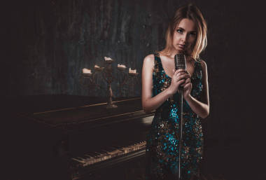 美丽的女人，与构成在钢琴 roo 的花式件高雅的连衣裙