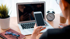 使用智能手机和笔记本电脑背景的女性手是工作场所表