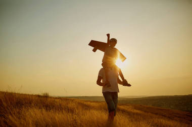 父亲与他的儿子在一个飞行员西装在日落自然