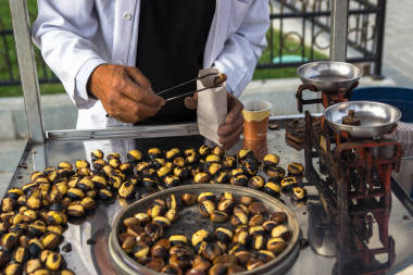 卖方把烤的栗子放到包图片