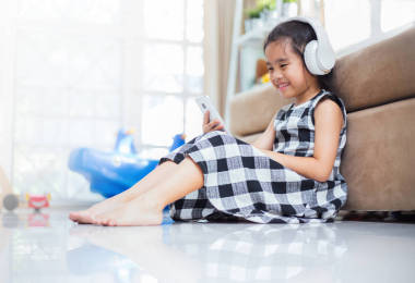 快乐的亚洲女孩使用耳机听音乐的智能手机在直播室