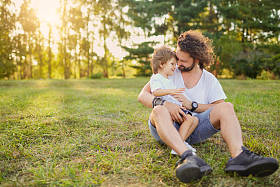 父亲的儿子在公园的草地上拥抱