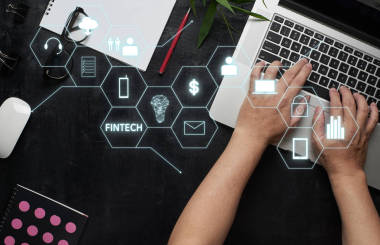 “Fintech”字在數(shù)字虛擬屏幕上以筆記本電腦、男手、筆記本、眼鏡、寫生本、黑色木桌為背景。高科技的經(jīng)營理念