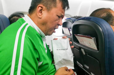 惡心的空氣疾病亞洲人嘔吐到嘔吐袋
