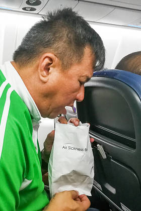 恶心的空气疾病亚洲人呕吐到呕吐袋