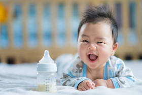 亚洲新生婴儿微笑与电源瓶牛奶