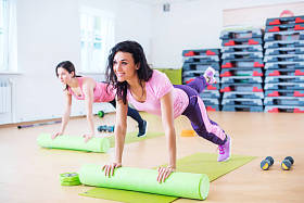 合适的女人使用泡沫辊板锻炼的地板上伸展