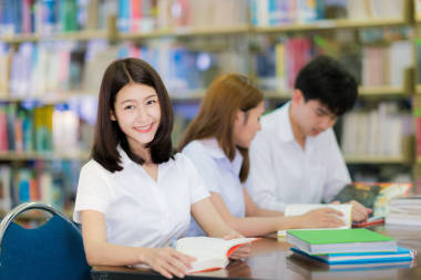 亞洲學(xué)生女士微笑和在大學(xué)的圖書館看書