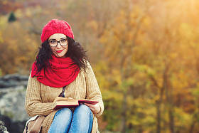 年轻漂亮的女人在公园里看书，喜欢阳光明媚的秋日