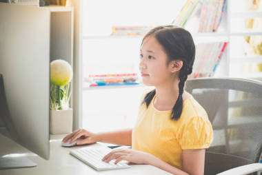 美麗的亞洲女孩在臺式計算機上工作