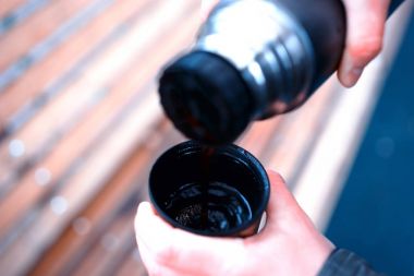 用滚烫的茶从热水瓶景背景填充杯
