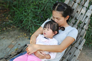母親和孩子的女孩躺在花園里木搖籃