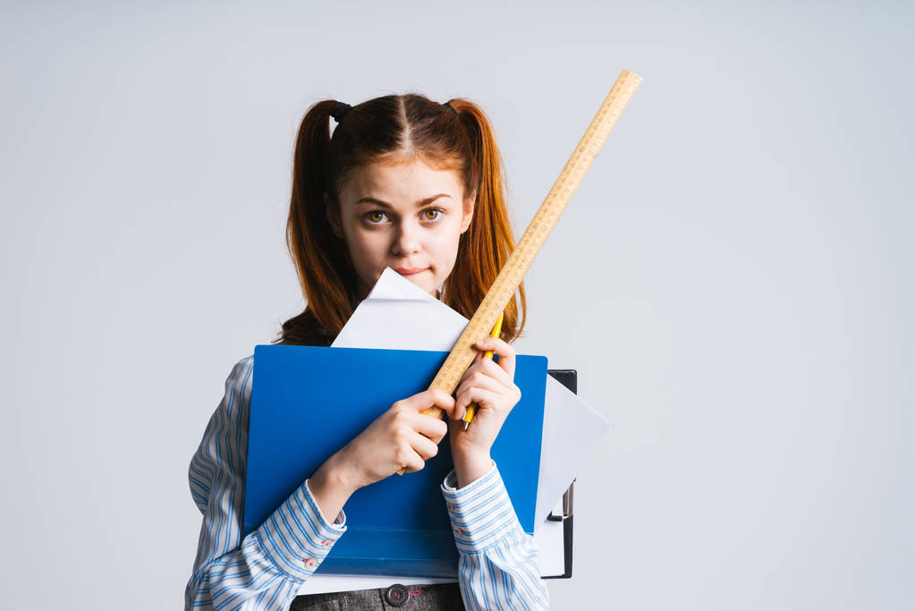 女学生与两个马尾辫，拿着一束的文件夹和一把尺子