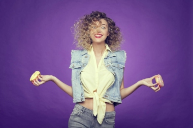 在紫色背景下手里擺著兩個(gè)甜甜圈的卷發(fā)女孩