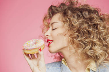 年輕的女人把臉放在甜甜圈圖片