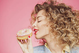 年轻的女人把脸放在甜甜圈图片