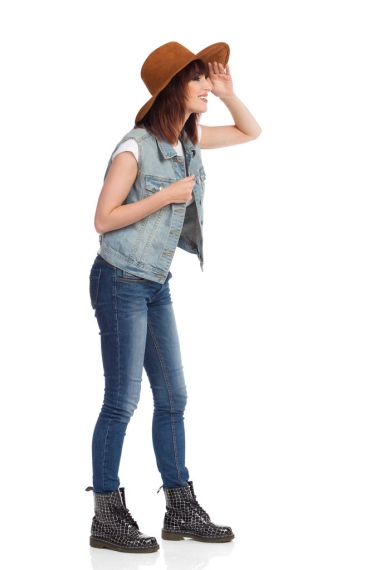 微笑的年輕女士在麂皮絨看著棕色的帽子