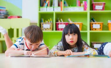 兩個(gè)孩子躺在地板和閱讀故事書在學(xué)齡前的 lib