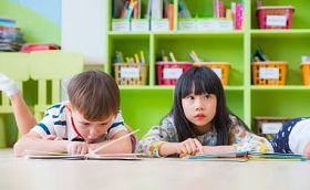 两个孩子躺在地板和阅读故事书在学龄前的 lib