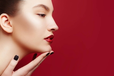 美丽的年轻女子和完美的化妆和红红的嘴唇。仕女画的华丽的黑发女子与清洁皮肤。红色背景