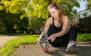 年輕女子賽跑者綁她準(zhǔn)備慢跑的鞋子