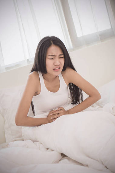 有胃疼的年輕婦女在臥室里撫摸著肚子