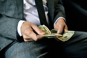 人在车的后面计数美元钞票