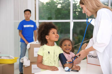 年輕的女人檢查小可愛(ài)的女孩。國(guó)外志愿服務(wù)概念