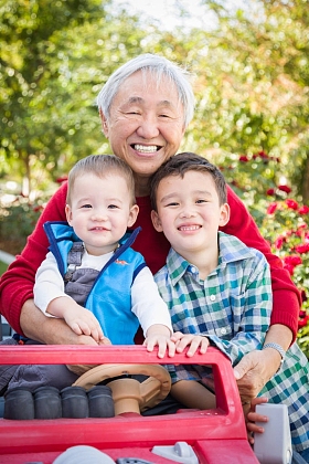 快乐的成年中国男子与他的混血孙子玩