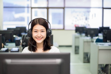 微笑亞洲女學(xué)生在學(xué)習(xí)的同時與計算機合影
