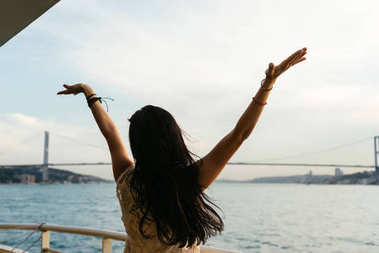 邮轮在海上享受旅游度假的船度假女人。用在自由的姿势张开双臂望着海洋自由无忧无虑快乐的女孩