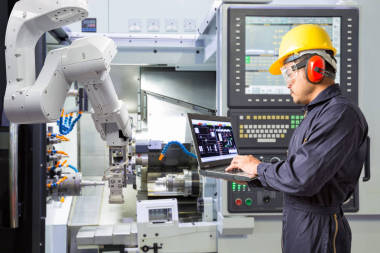 維修工程師使用筆記本電腦控制自動機械手與 Cnc 機器在智能工廠。行業(yè)4.0 理念