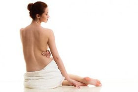 裸体女人坐在白色的毛巾