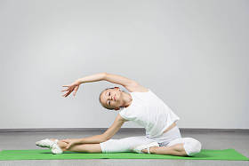 年轻姑娘做绿色瑜伽垫上练习照片