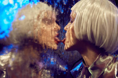 接近未来的霓虹灯点燃的肖像一个女孩与白色鲍勃发型舔湿玻璃