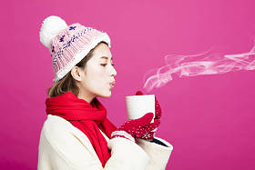 穿着暖和的毛衣的女人喝一杯热茶