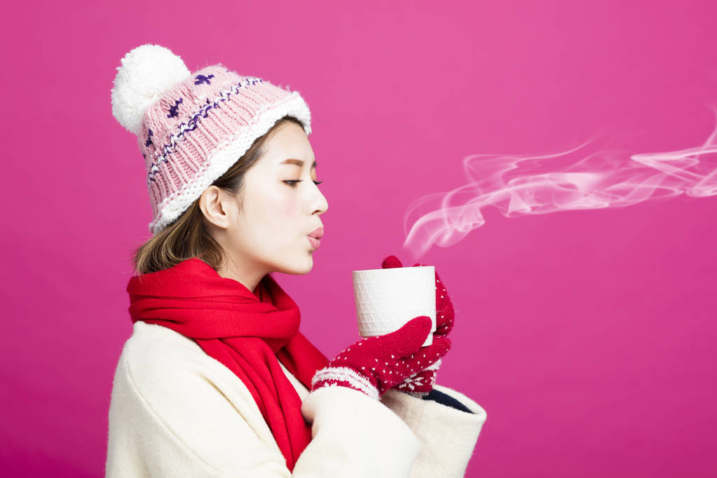 穿着暖和的毛衣的女人喝一杯热茶 穿着暖和的毛衣的女人喝一杯热茶