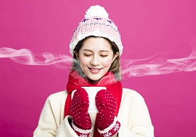 穿着暖和的毛衣的女人喝一杯热茶