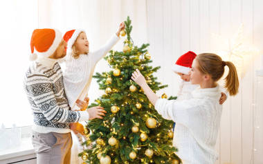 家庭母親父親和孩子裝飾一棵圣誕樹在