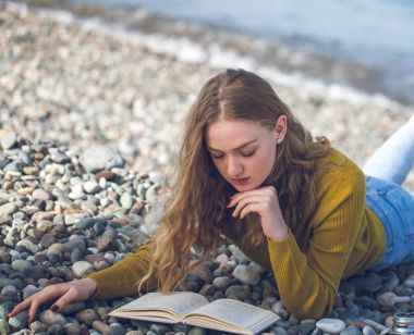 美麗的金發(fā)女郎正在沙灘上看書